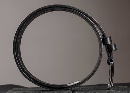 Leather belt twisted into a circle on a grey background