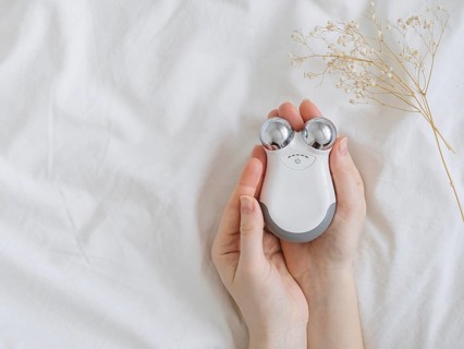 Microcurrent concept. Face massager with micro currents for home use and skincare on white bed.