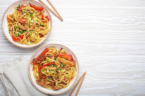 Two bowls with Chow Mein or Lo Mein, traditional Chinese stir fry noodles with meat and vegetables,