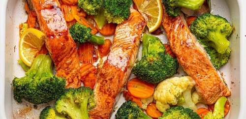 Top view close up of healthy baked fish salmon steaks, broccoli, cauliflower, carrot in casserole