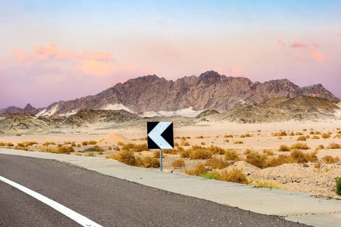 Sign on road in the desert of Egypt at sunset