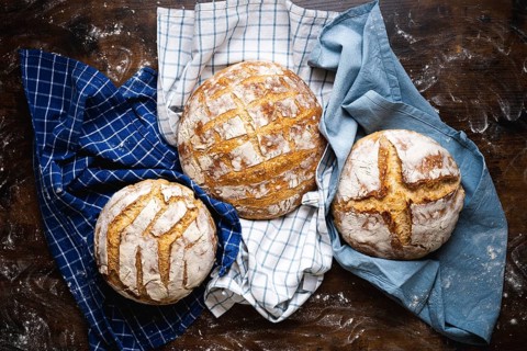 Above view with three homemade sourdough loaves of bread on towels. Freshly baked and delicious