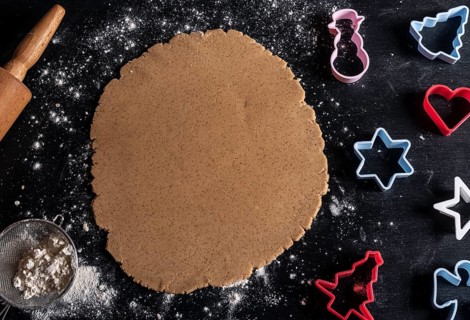 Black wooden table above view with multicolored cookie cutters and gingerbread batter
