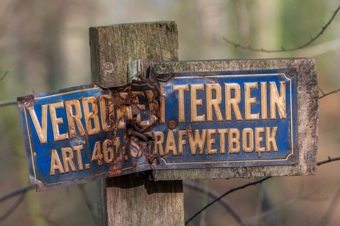 Old weathered sign forbidden entry in Dutch language on a pole