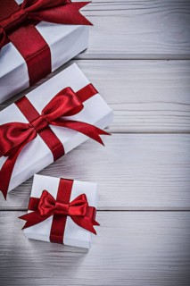 Present boxes with tied bows on wooden board holidays concept