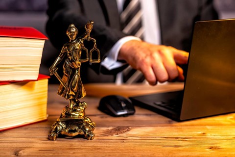 Office of a lawyer with books and a statue of Lady Justice, goddess Justitia, on the desk