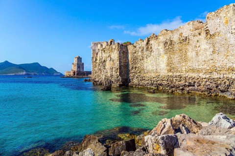 The watchtower is built on long cape in the sea. Sea shoal beautiful azure color. Venetian fort
