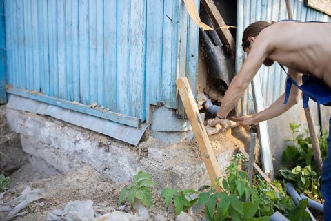 A man repairing the exterior corner of a wooden building