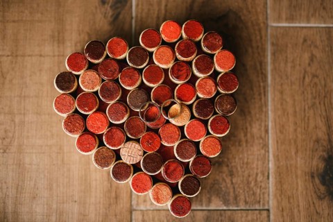 Wedding rings of the bride and groom on a pattern of hearts made of wine bottle corks on a wooden