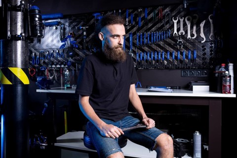 Portrait of small business owner of young man with beard. Guy bicycle mechanic workshop worker