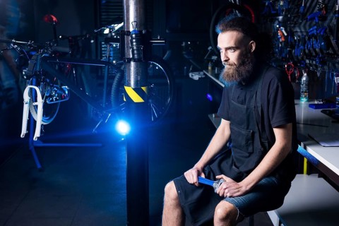 Portrait of small business owner of young man with beard. Guy bicycle mechanic workshop worker