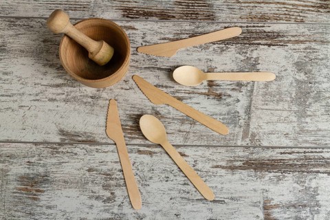 Wooden mortar with a pusher and other tools. Knives and spoons. Top view flat lay
