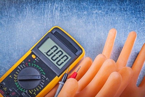 Digital multimeter insulating rubber gloves on metallic background electricity concept