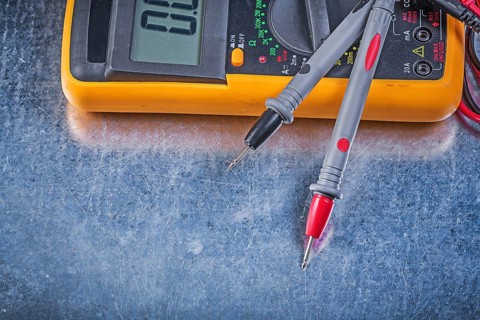Digital electric tester test leads on metallic background