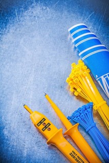 Yellow electrical tester self-locking cable ties blue construction plans on metallic background