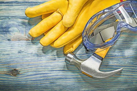 Protective glasses leather gloves claw hammer on wooden board construction concept