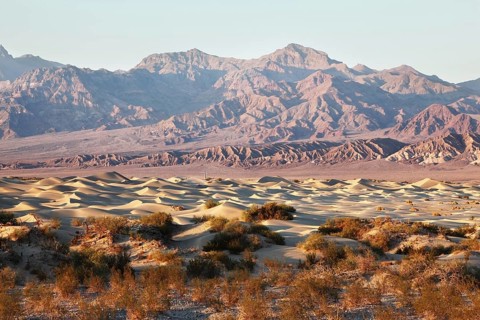 The famous Death Valley in California. Sand dunes and ancient mountains. Pink sunrise