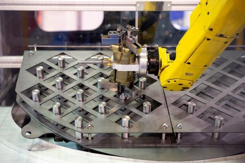 Yellow robotic arm arranges metal elements after being produced. Automatic industrial machinery