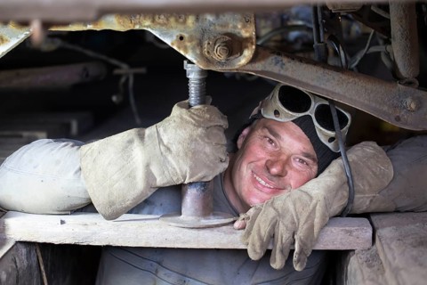 A male car mechanic repairs a car in a garage