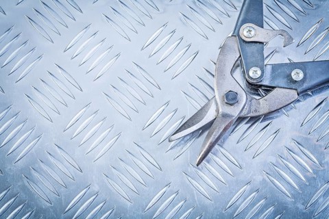 Flat nose pliers on corrugated metal background construction concept