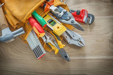 Construction tools in leather toolbelt on wood board