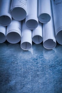 Pile of rolled engineering drawings on scratched silver-metal background building and architecture