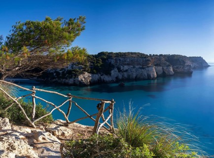 A landscape view of the idyllic Cala Macarella in southern Menorca with a hiking trail in the