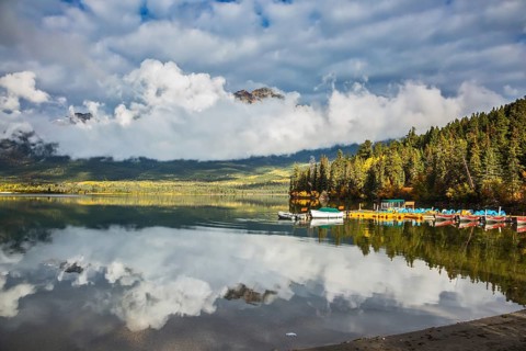 Pyramid Mountain reflected in Pyramid Lake. Wooden boat dock with moored pleasure boats and benches