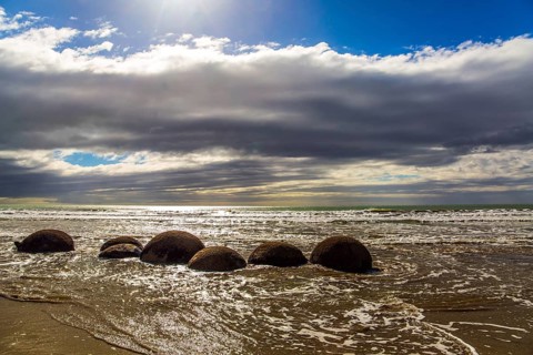 Moeraki boulders. Ocean tide begins. Group of large round boulders on the coast of the South Island