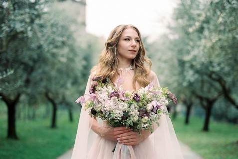 Bride with a bouquet of flowers in an olive grove.