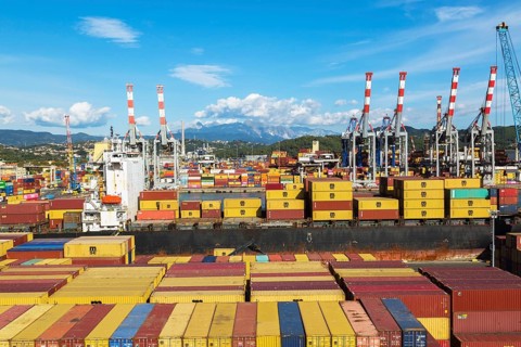 High angle view of stacked rectangular metal box shipping containers on dock waiting to be loaded