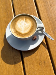 Coffee drink Cappuccino Cappuccio with flower pattern in milk foam, next to it single roasted