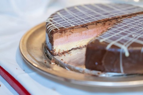 Close-up of an ice cream cake with chocolate, strawberry filling and decorative lattice pattern,