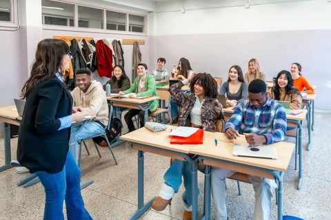 Multi ethnic university students attending a lesson with their professor, participating actively