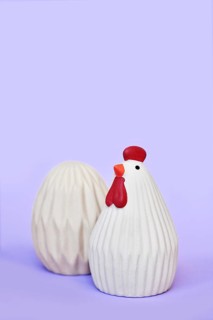 Ceramic Easter chicken and egg decoration objects on purple background with copy space