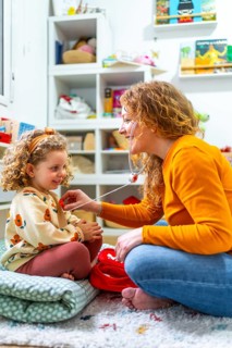 Vertical photo of a caucasian mother listening the beat of daughter heart with fake stethoscope