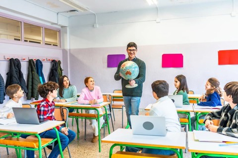 Geography teacher engaging students while holding a globe, fostering learning and understanding in