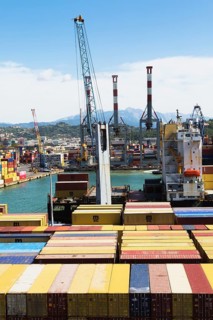 High angle view of stacked rectangular metal box shipping containers and gantry cranes on dock in