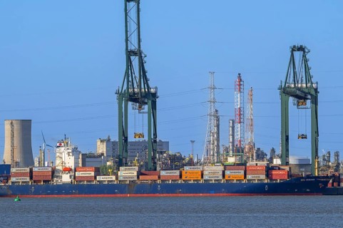Gantry cranes and stacked containers on container ship docked at container terminal in the port of