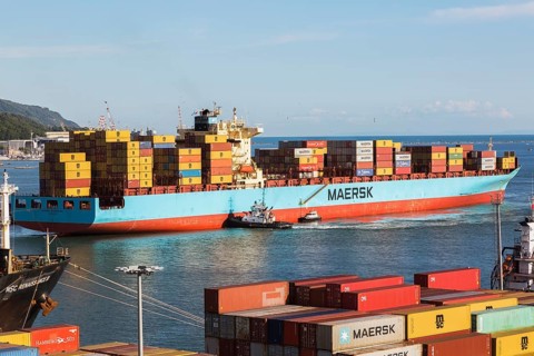 Maersk Serangoon cargo ship loaded with metal box shipping containers being guided by pilot boats