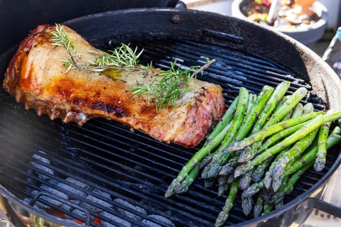 Barbecue with Easter roast. Rack of lamb and green asparagus grilled on an outdoor kettle barbecue.