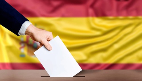 Hand holding ballot in the ballot box with the flag of Spain in the background. Spain general