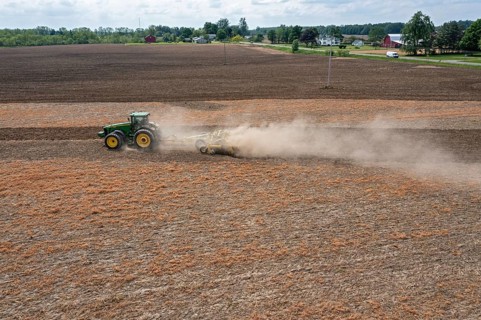 Hudson, Michigan, A cloud of dust blows behind the tractor as a farmer tills his field