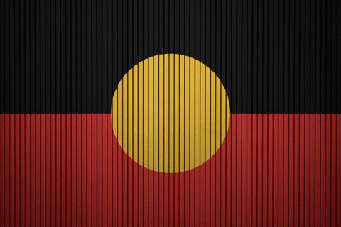 Australian Aboriginal flag painted on the cracked grunge concrete wall