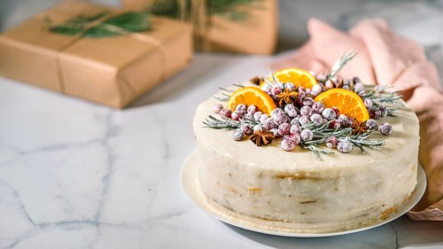 Winter homemade cake on white marble background. White cream christmas cake decored rosemary,