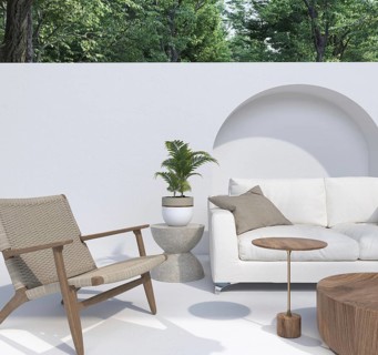 Patio setup with a white sofa, armchair, and plants in a serene environment