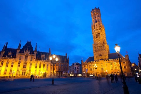 The provincial courthouse and belfry are illuminated at dusk in grote markt, the city center of