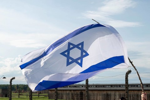 The flag of Israel in the background barbed wire fence of a concentration camp