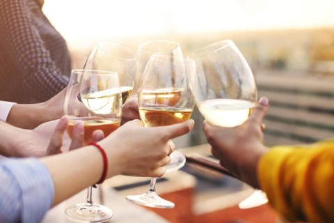 Group of anonymous people clinking wineglasses and proposing toast during party on rooftop