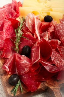 Assorted meat, appetizer, prosciutto, salami and ham, with maasdam cheese and olives, on a wooden